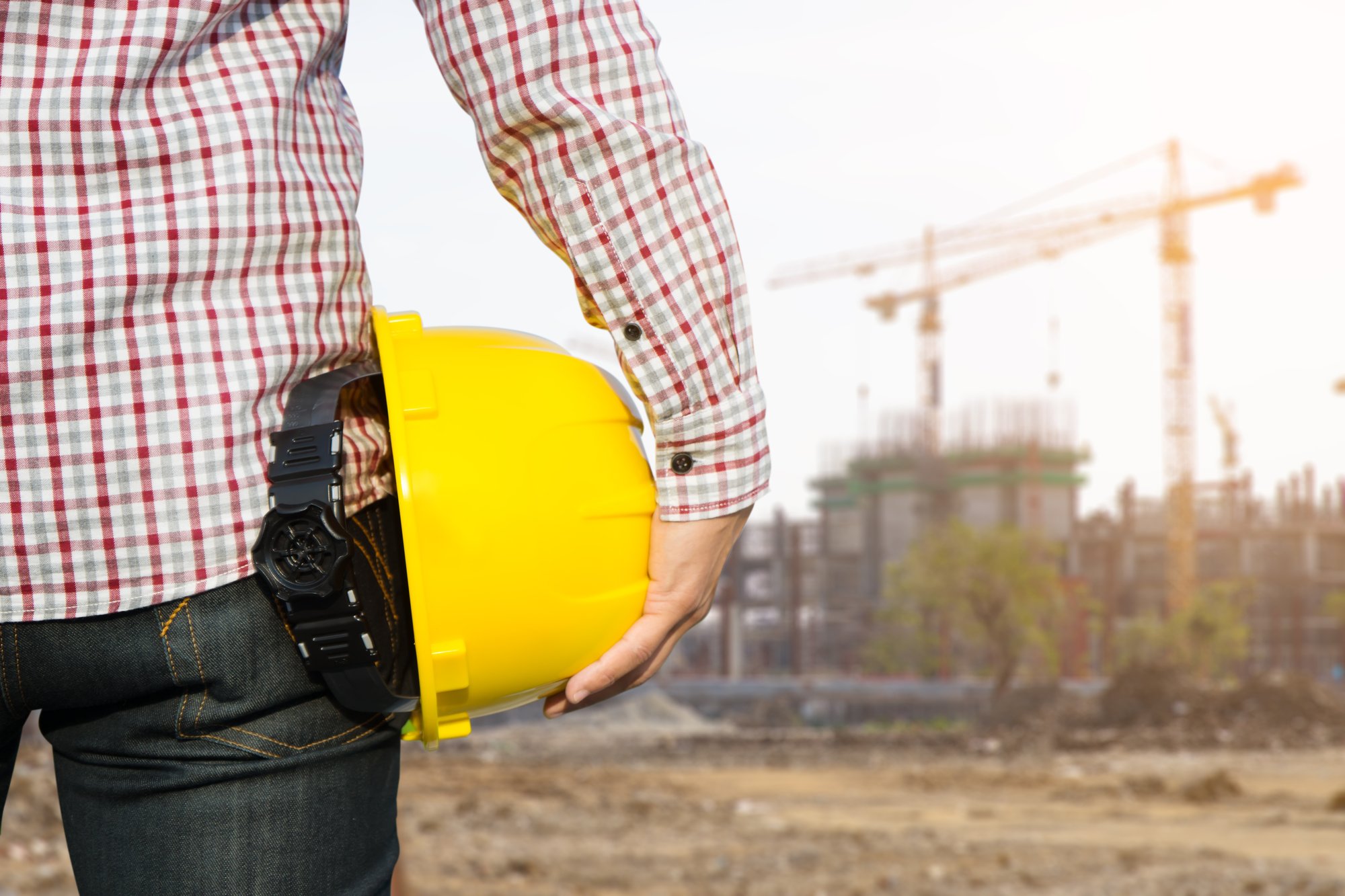 hand-s-engineer-worker-holding-yellow-safety-helmet-with-building-site-background